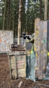 Paintball-pelaaja suojan takana metsäkentällä.