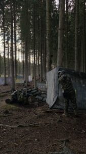 Paintball-pelaaja suojan takana metsäkentällä.